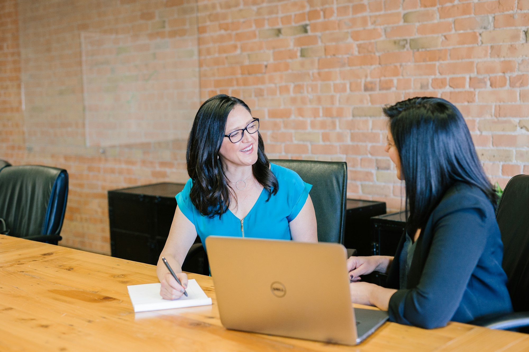 Two women in a business meeting at a table, one in a suit jacket