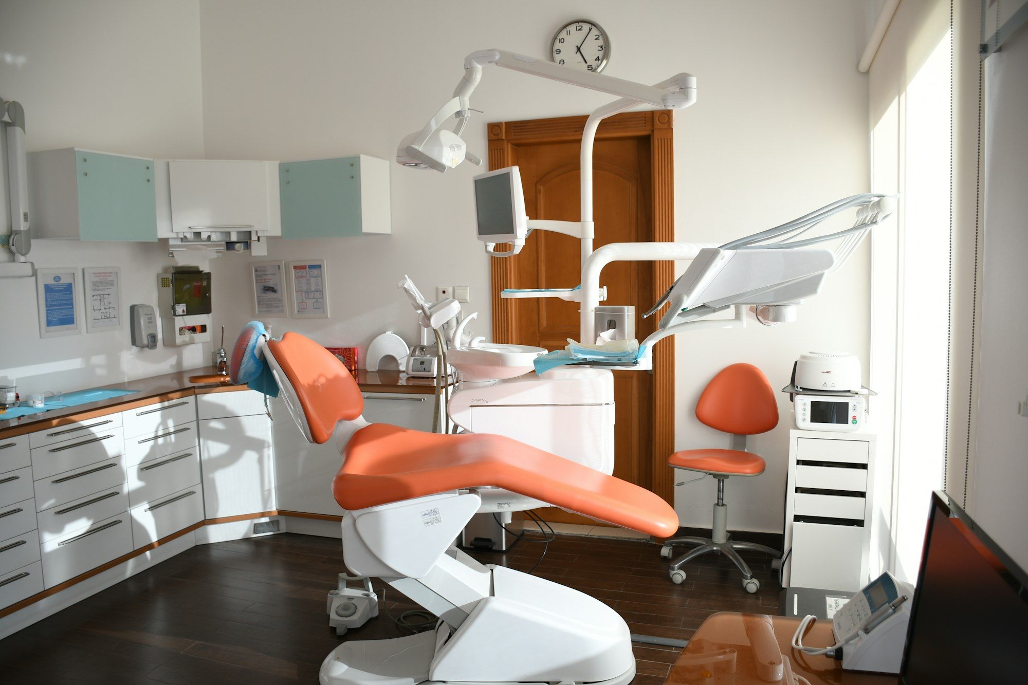 Orange dental chair and medical equipment in a bright, modern clinic room