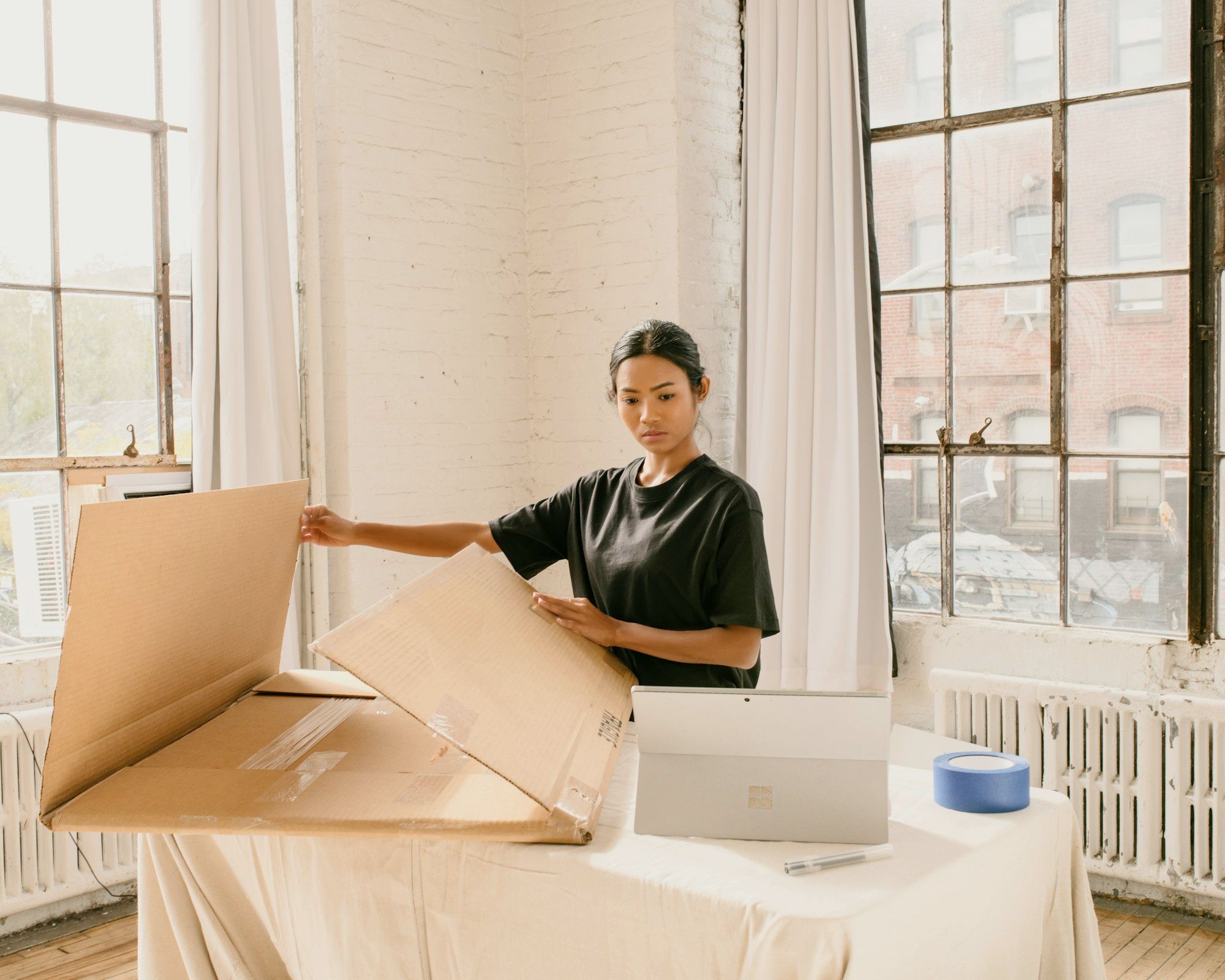 Small business owner standing beside a cardboard shipping box and laptop on a table