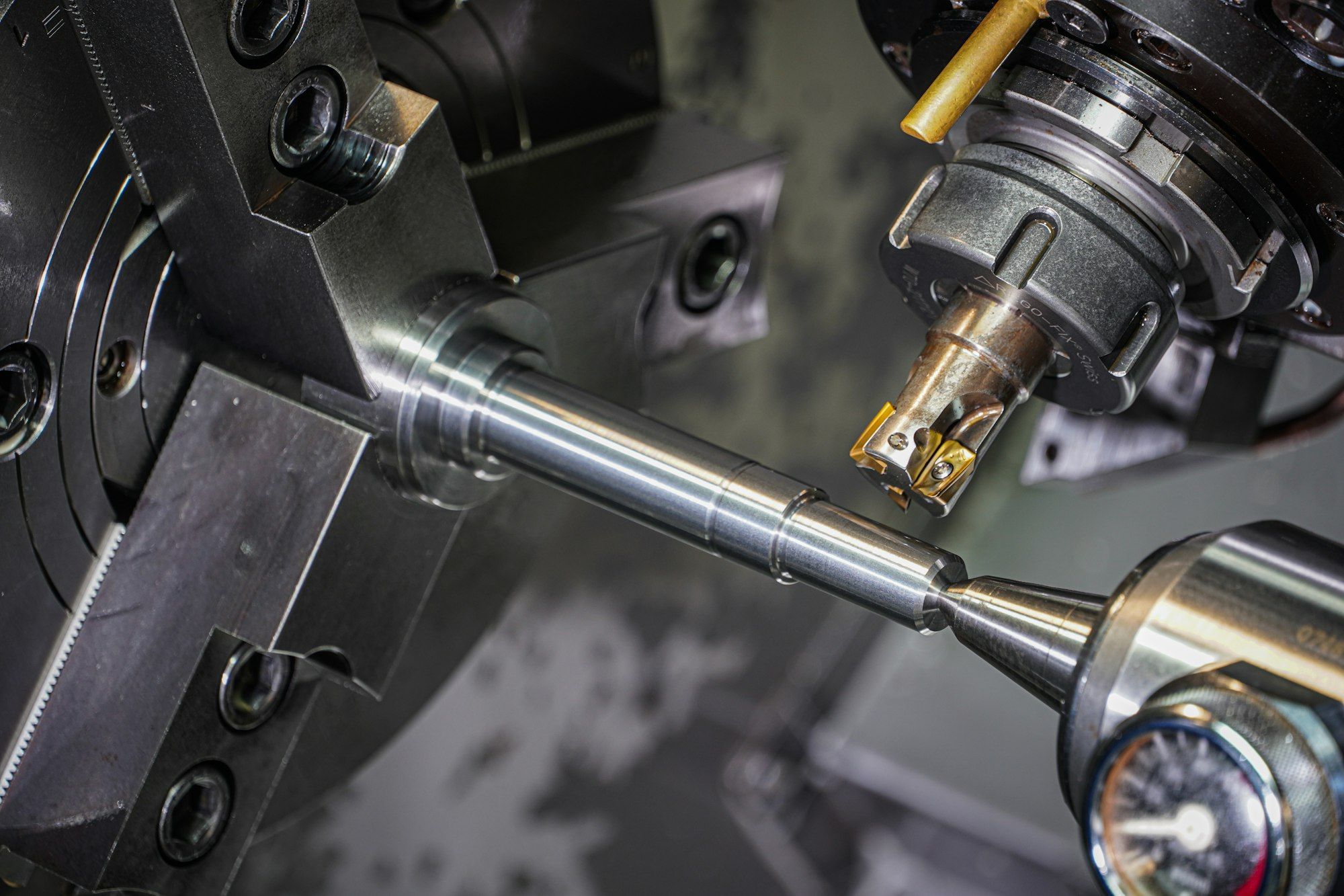Metal rod held in a lathe chuck being machined by a cutting tool