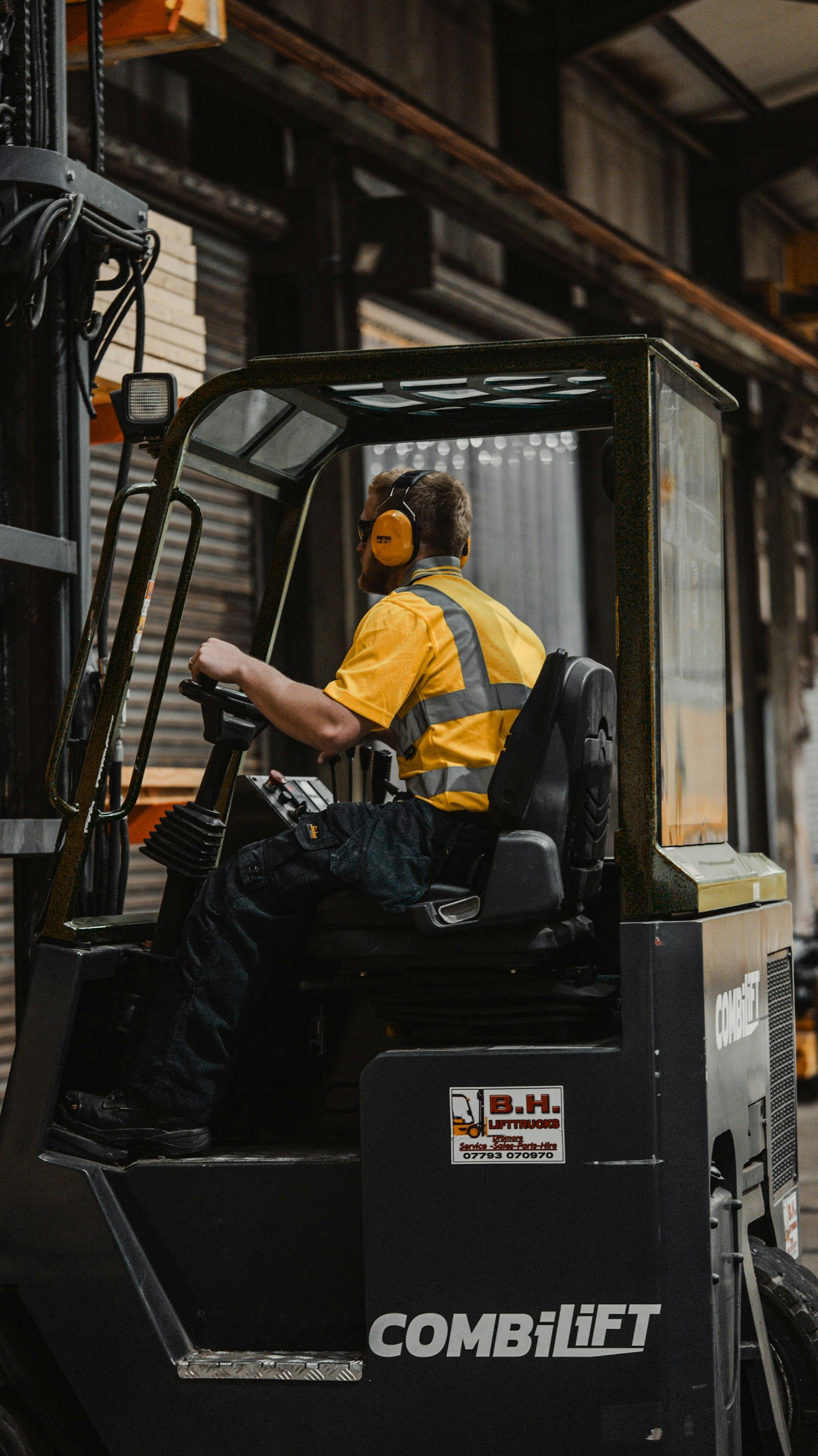 Worker in a yellow high-visibility shirt operating a forklift inside a warehouse