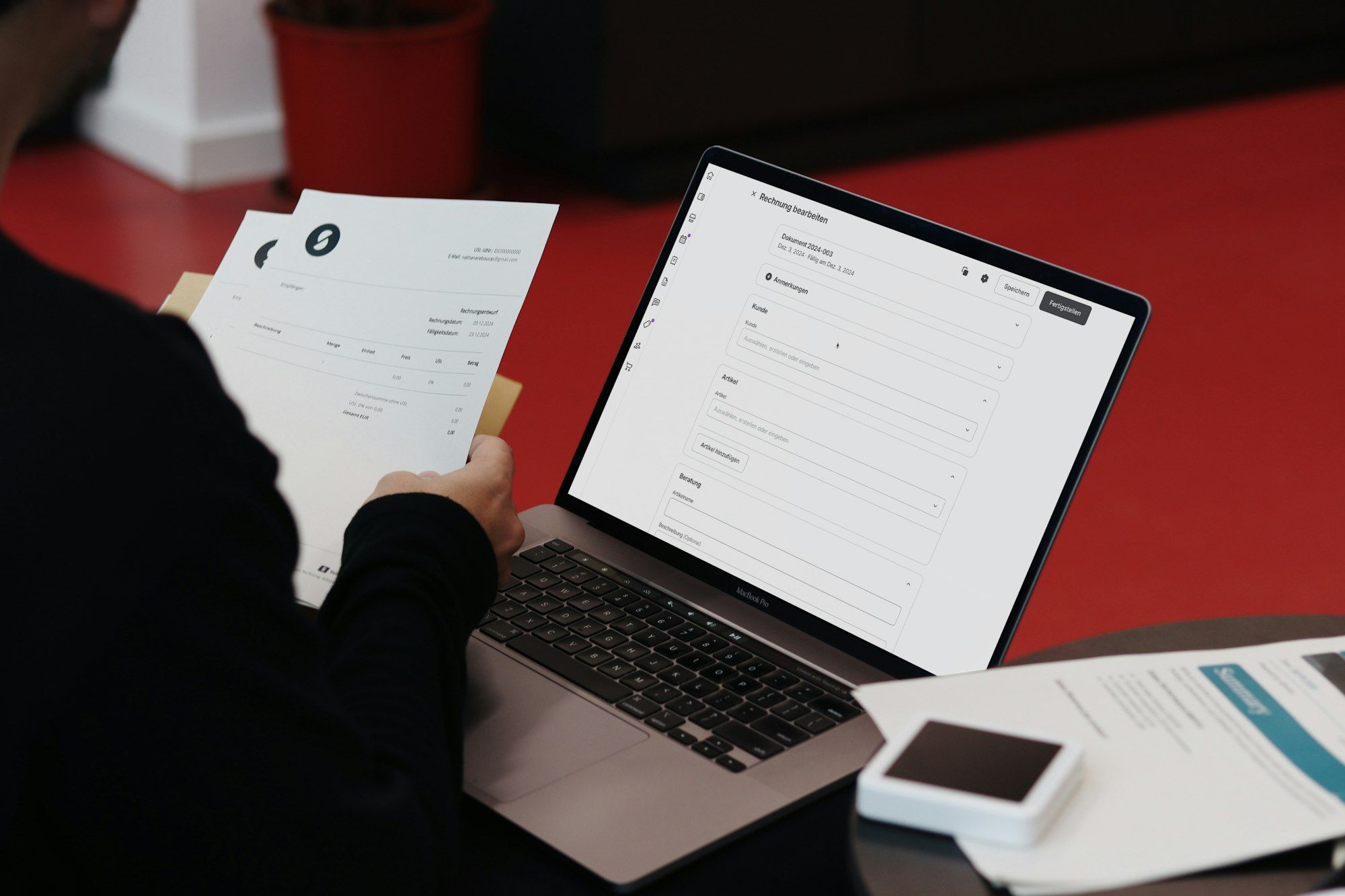 Person at a desk working through paper invoices beside an open laptop
