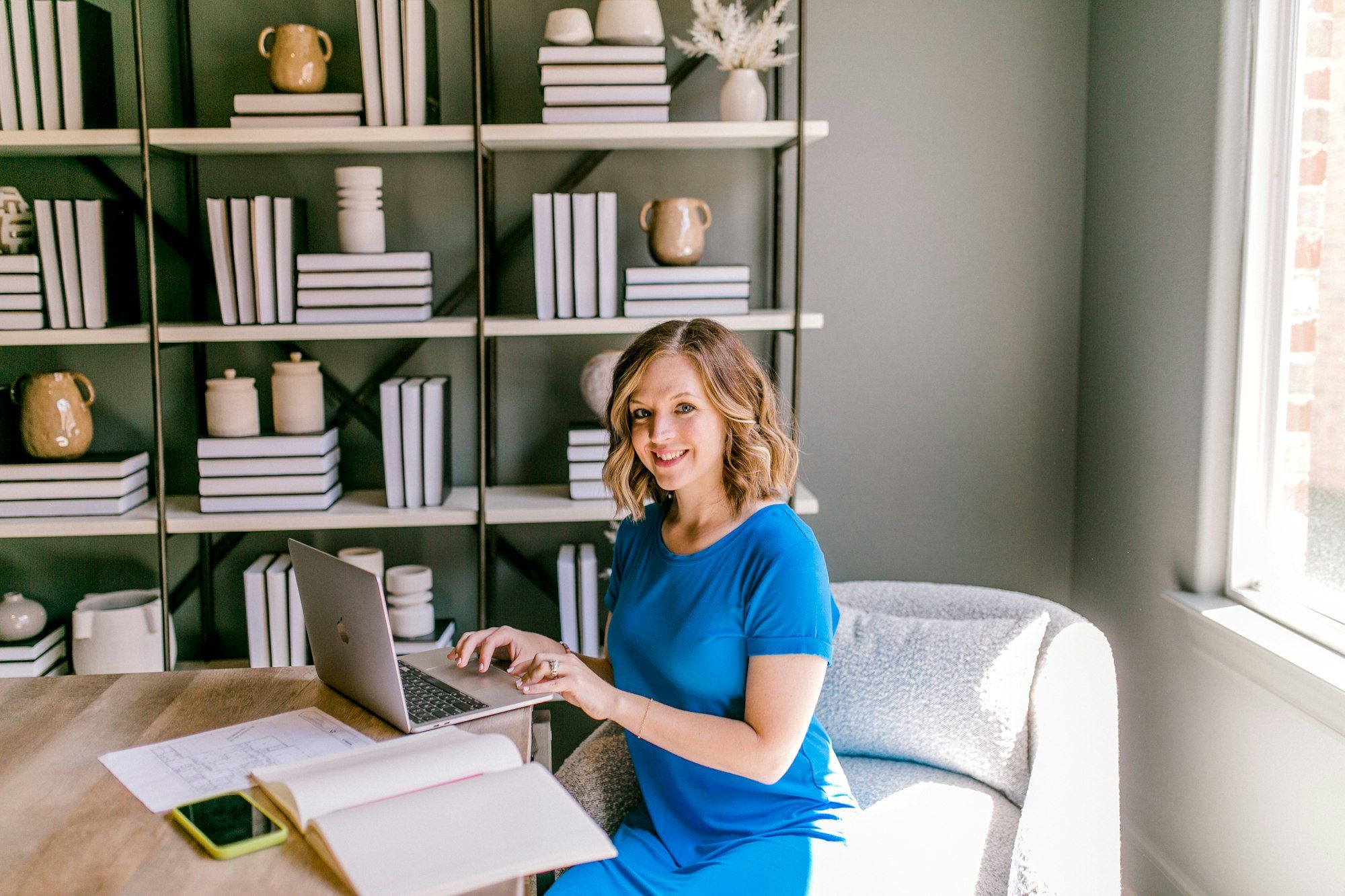 Smiling woman working on a laptop at a desk in a bright workspace