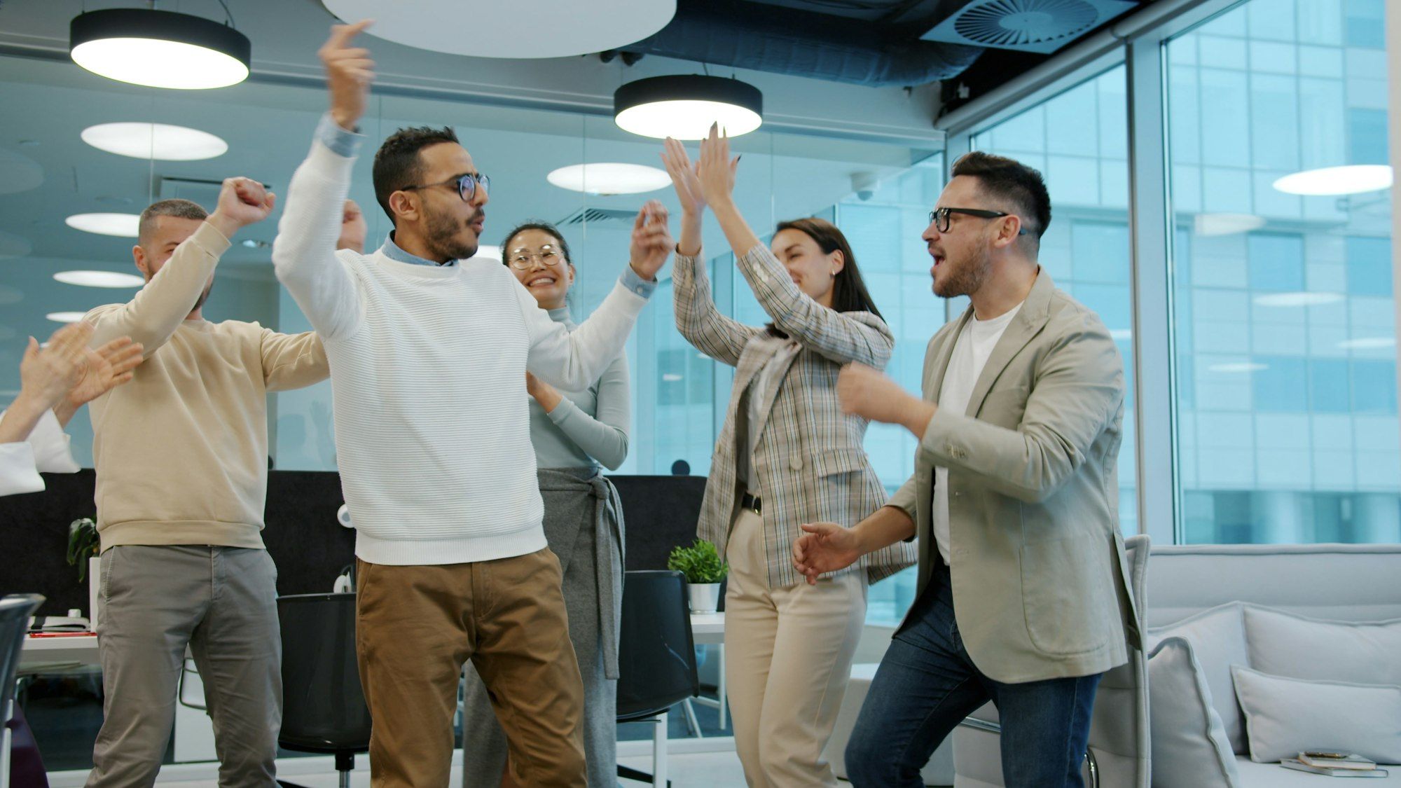 Diverse group of colleagues celebrating a success together in a modern office
